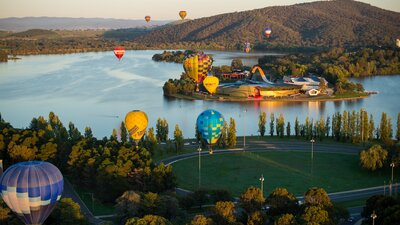 Hot air balloons above lake and museum