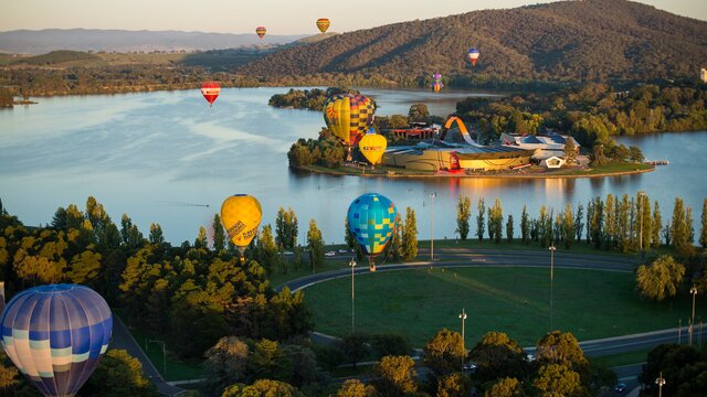Hot air balloons above lake and museum