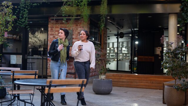 Two people wander through Braddon sipping coffee.