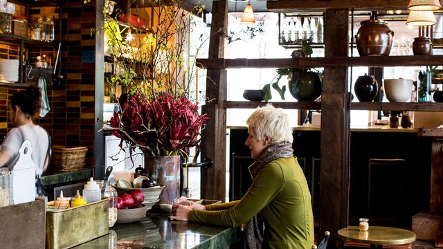A woman sitting at the counter in a hipster cafe.