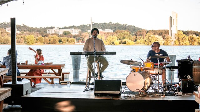 Two person band playing in an outdoor venue by the lake