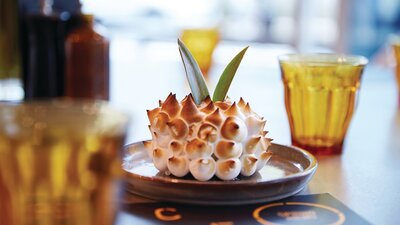 A specialty cake served on a plate with some glasses of water on a table at Space Kitchen.