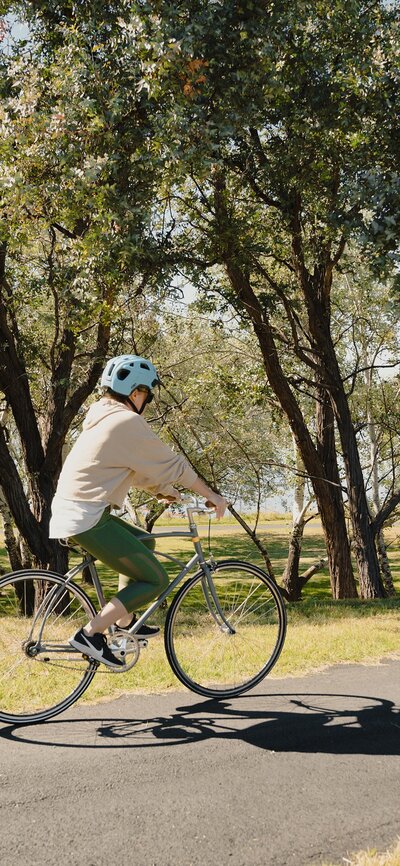 A woman riding a bike through a leafy park.