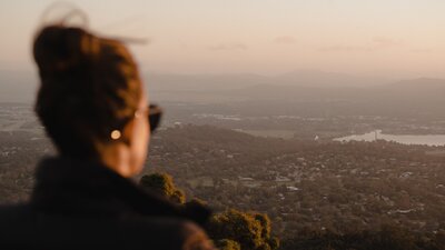 A woman with sunglasses looking out across Canberra.