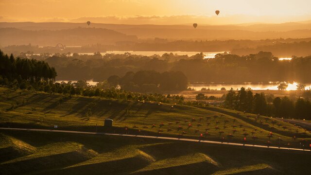 The National Arboretum and its surrounds at sunset with a few hot air balloons dotted on the skyline.