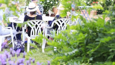 A group of people enjoying a meal and wine outdoors in the garden and vineyards of Brindabella Winery.