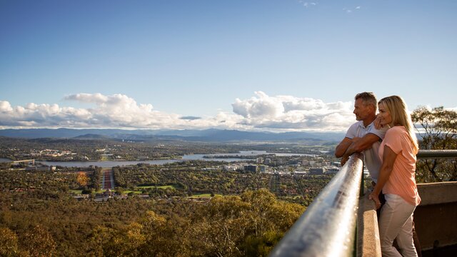 A couple looking out over Canberra's suburbs and lakes.