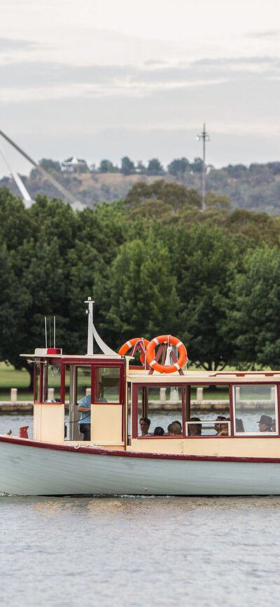 A boat sailing on the lake with a view of Parliament House in the background.