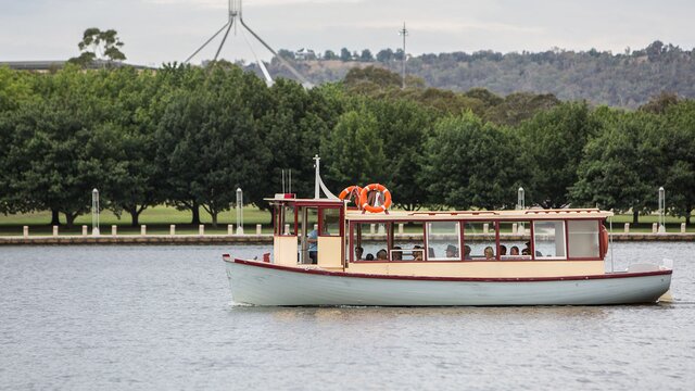 A boat sailing on the lake with a view of Parliament House in the background.