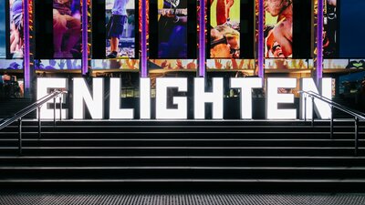 Large neon letters spelling out Enlighten on the steps of the National Library of Australia