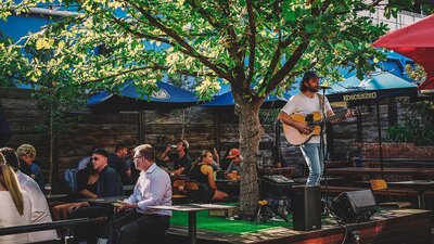 Live music in the outdoor dining and beer garden area of Assembly in Braddon, with groups of friends enjoying themselves.