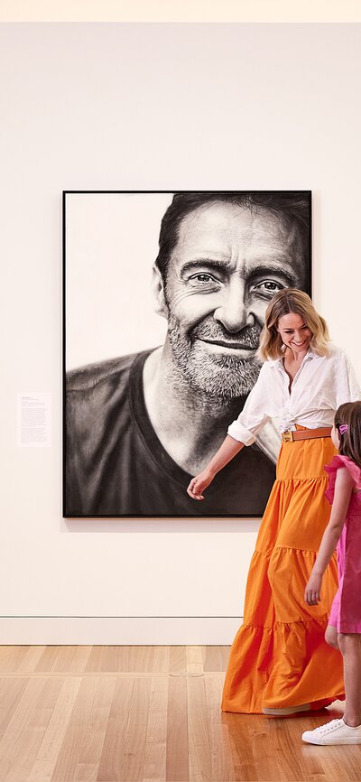 A mother and daughter in front of a portrait in a gallery 