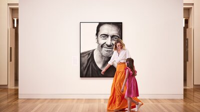 A mother and daughter in front of a portrait in a gallery