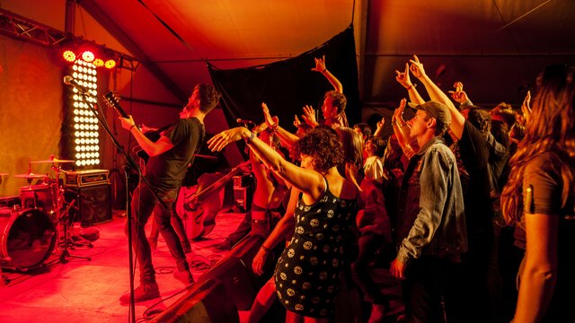 National Folk Festival | © Richard Poulton Crowd cheering enthusiastically toward performer on stage at the Folk Festival, under red stage lights. | © Richard Poulton