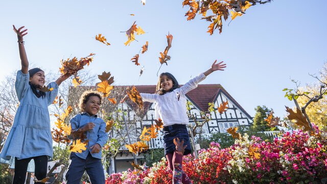 Three kids playing with autumn leaves