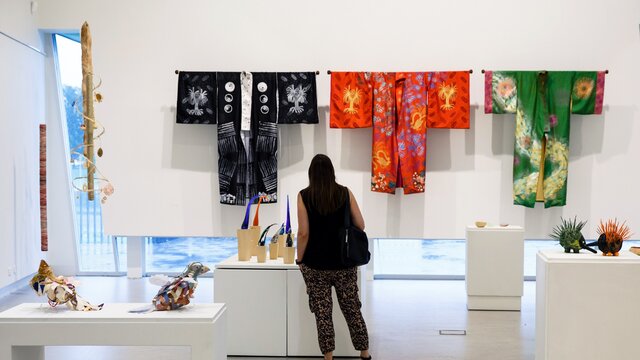 A woman looks at colourful art hanging on the wall at a gallery