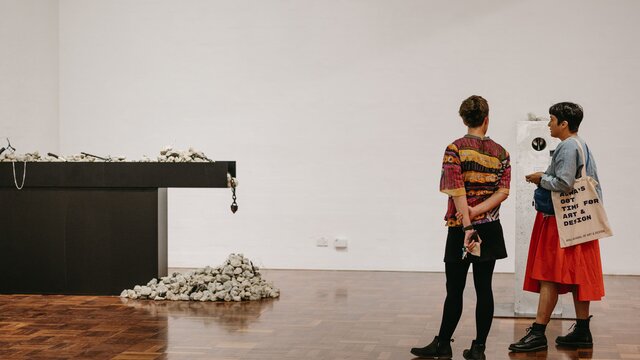 Two visitors observing art at the ANU School of Art and Design.