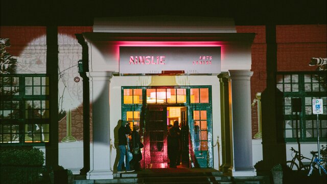 The front facade of the Ainslie Arts Centre, lit up with projected lights and shapes.