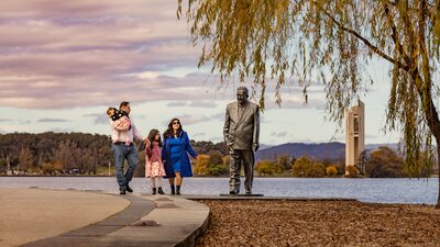 A family is walking alongside picturesque Lake Burley Griffin