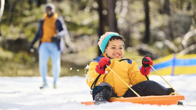 A small child is on a toboggan in the snow.