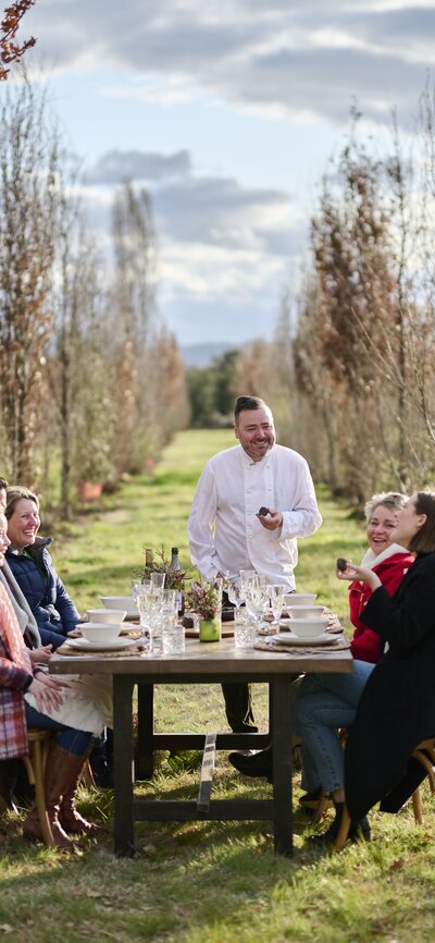 A group of friends sitting down at a table on a truffle farm