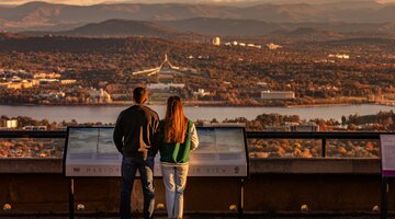 A couple standing at the lookout of Mount Ainslie with Canberra in the background