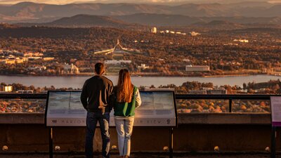 A couple standing at the lookout of Mount Ainslie with Canberra in the background